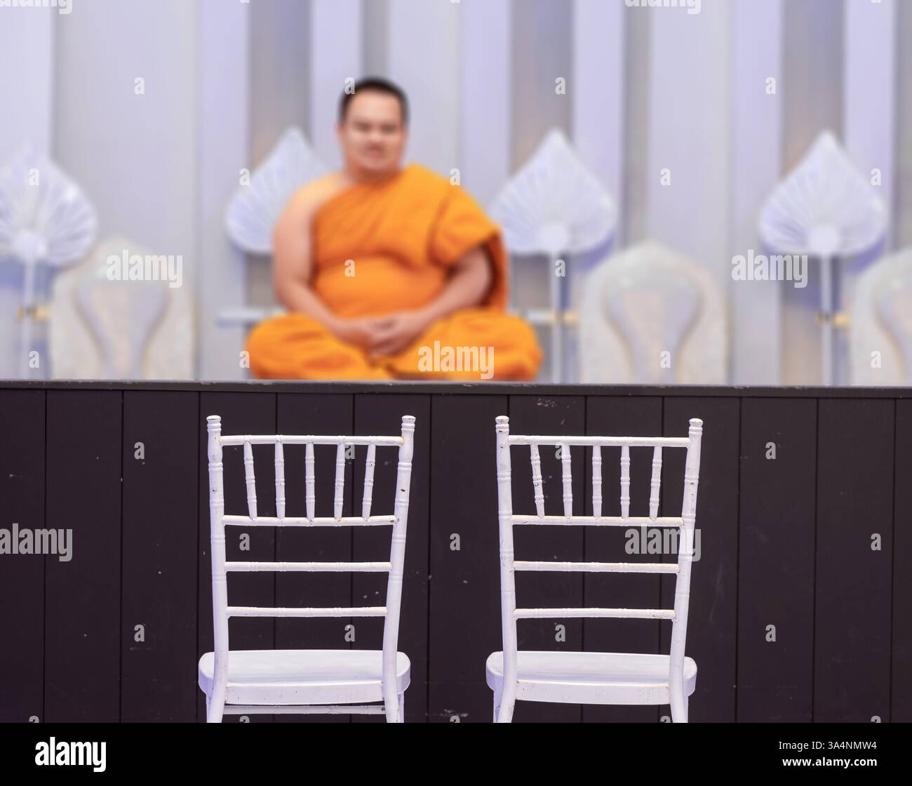 Une paire de chaises blanches sous un podium avec un moine bouddhiste prêt pour un rituel de mariage Banque D'Images