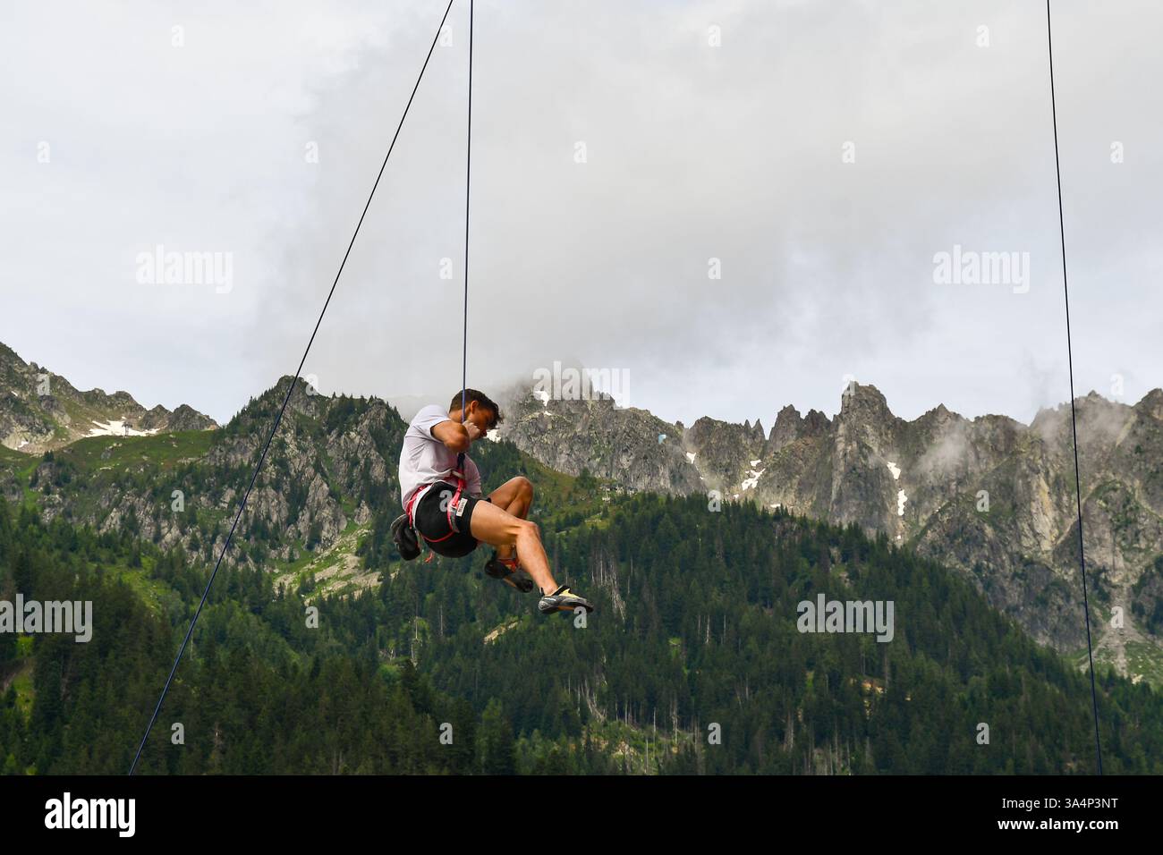Grimpeur en compétition dans la Coupe du monde d'escalade IFSC de vitesse et de tête, avec les aiguilles en arrière-plan, Chamonix, haute Savoie, France Banque D'Images