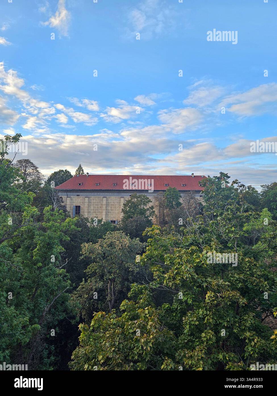 Une vue depuis le château de Prague montrant l'arrière de la salle de bal, avec son architecture historique entourée de verdure et d'espaces ouverts. Banque D'Images