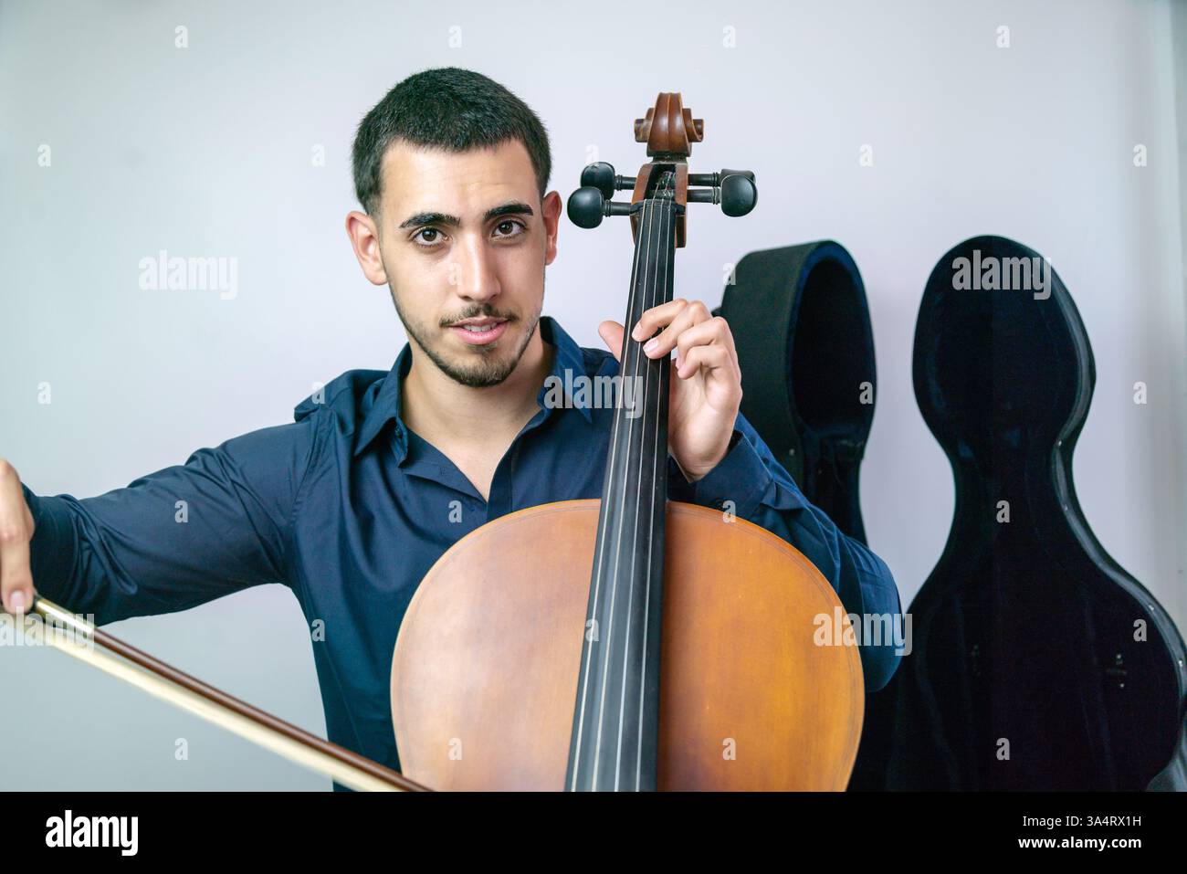 Jeune musicien jouant du violoncelle avec arc et cordes sur fond blanc.. Banque D'Images