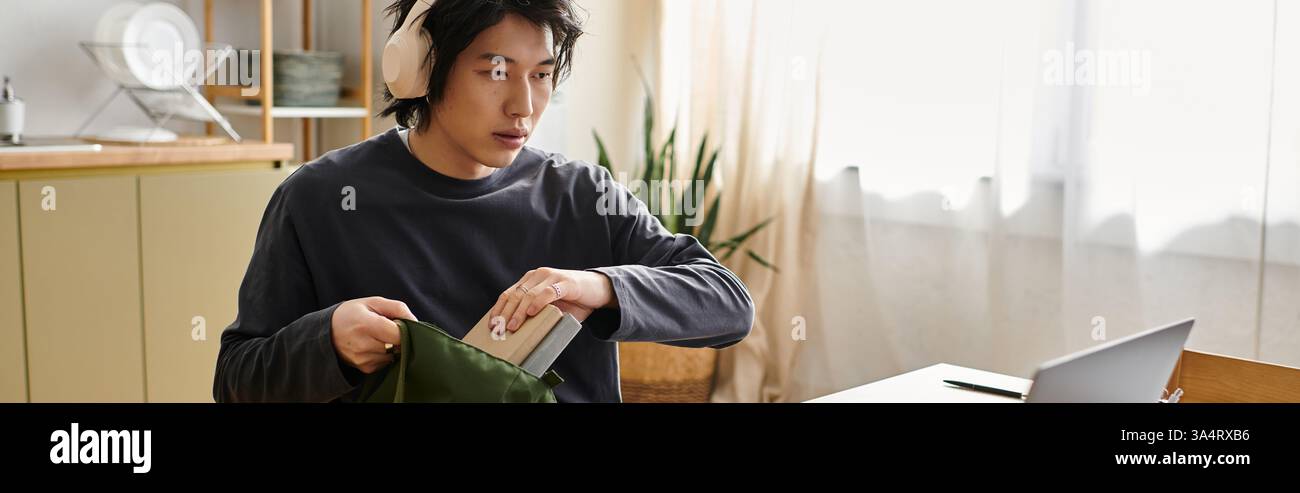 Concentré jeune homme se prépare pour des études en ligne tout en étant assis à son espace de travail à la maison, bannière Banque D'Images