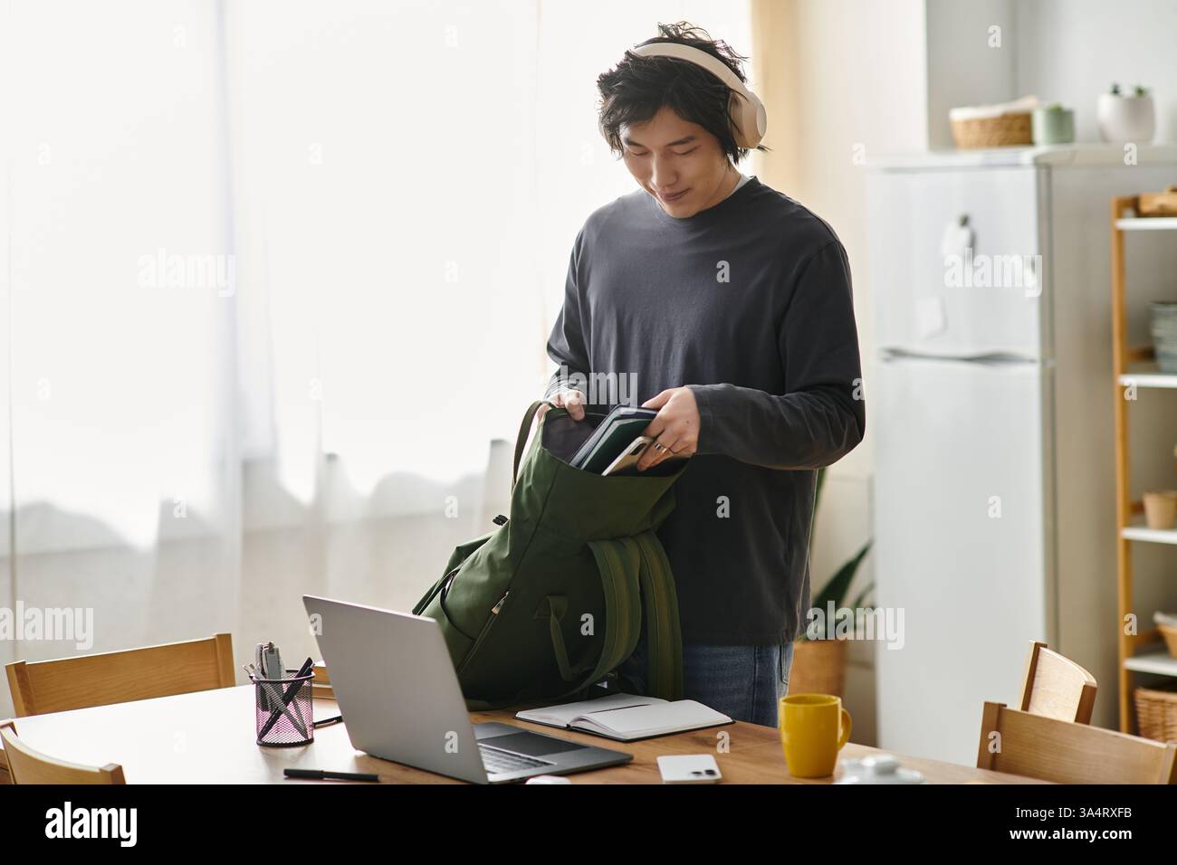 Jeune homme prépare son matériel d'étude tout en assistant à un cours en ligne à la maison. Banque D'Images