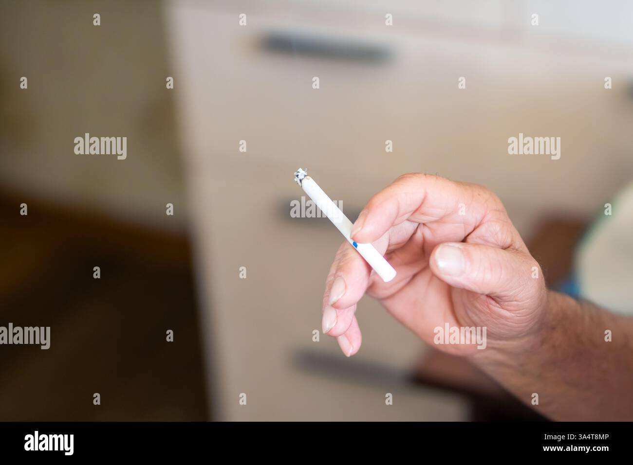 Une vue rapprochée d'une main tenant élégamment une cigarette, capturant un moment serein de contemplation profonde Banque D'Images
