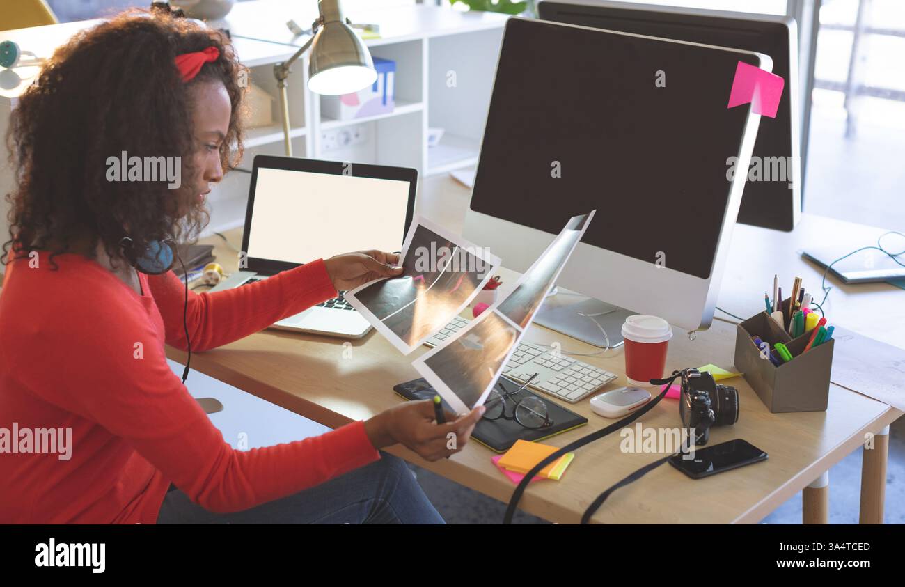 Créatif professionnel examinant des impressions de conception au bureau moderne avec technologie, espace de copie Banque D'Images