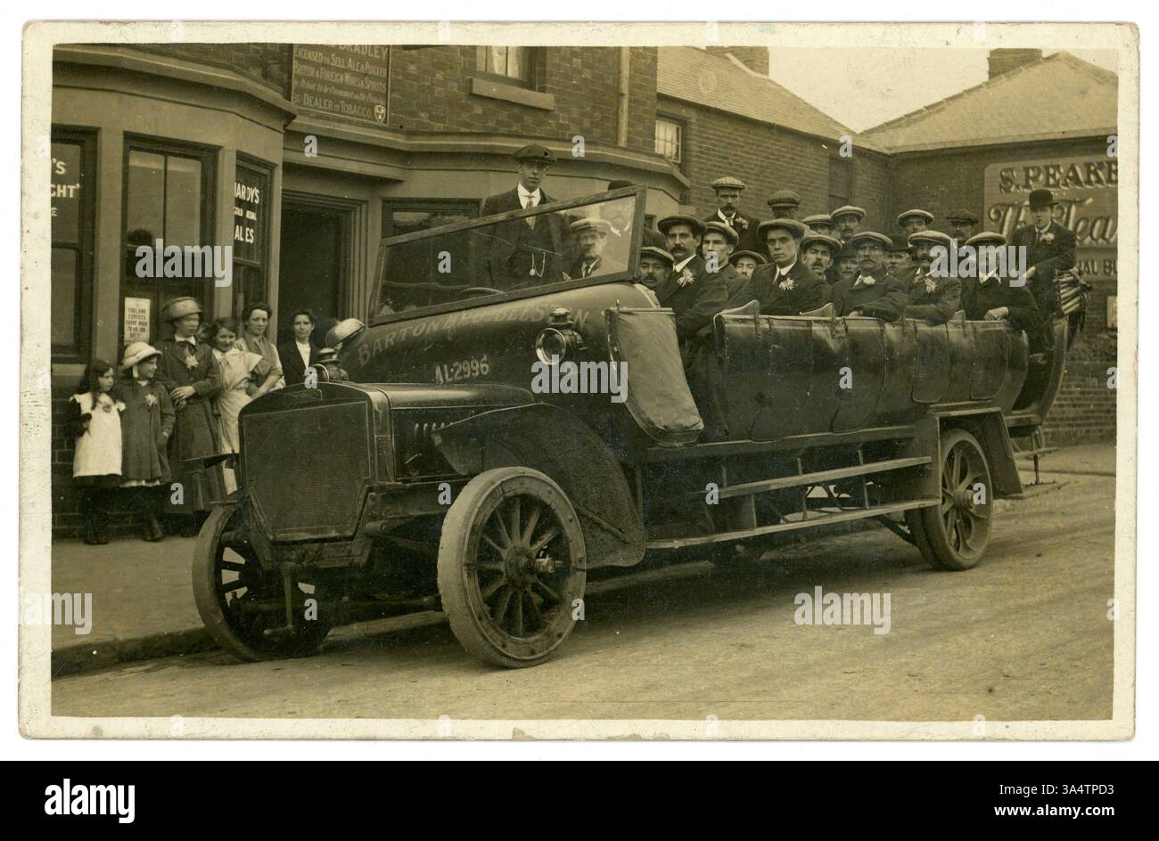 Original WW1 carte postale de Daimler charabanc de la société Nottingham, Barton Bros Beeston - signe à l'avant du véhicule. Dans la vitrine se trouve une affiche demandant « L'Angleterre attend de chaque homme qu'il fasse son devoir » et les ourlets à hauteur de la cheville indiquent la photographie datée vers 1917 - 1919. Les hommes ont l'air sombres et portent un chrysanthème dans leurs revers, comme le sont certaines des passantes. Deux des hommes ont une pulvérisation de fleurs plus élaborée 'boutonnière'. Est-ce une sortie de souvenir ou une fête de mariage de marié et meilleur homme - (les gens ne souriaient pas beaucoup dans les premières photos) ? Beeston, Nottingham, Royaume-Uni Banque D'Images