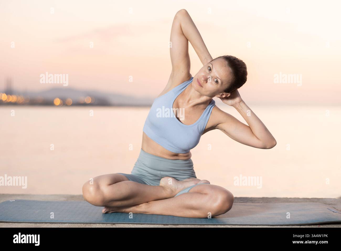 Heureuse jeune femme expérimentée professeur de fitness effectue le yoga parshvottanasana assis sur la plage le matin Banque D'Images