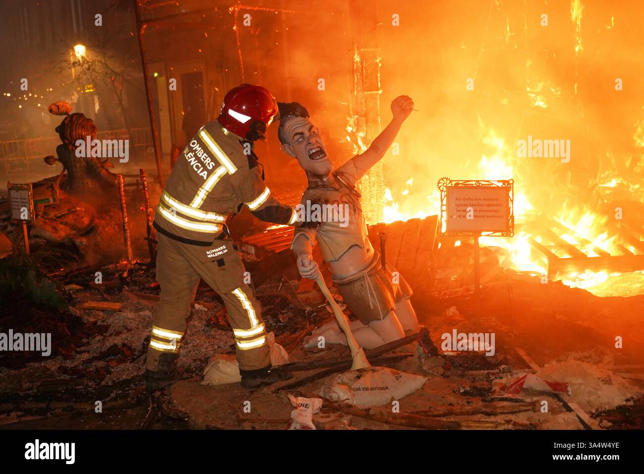 A firefights grabs a cardboard sculpture known as a "Ninot" depicting Spain's Prime Minister Pedro Sanchez which didn't burn during the Fallas festival in Valencia, Spain, on Wednesday, March 19, 2025. Five months after deadly floods ravaged Valencia, the Spanish city is hosting its biggest celebration of the year: Las Fallas. Sculptures were built using wreckage from peoples' homes and lampoon politicians accused of mishandling the catastrophe. (AP Photo/Alberto Saiz) Banque D'Images