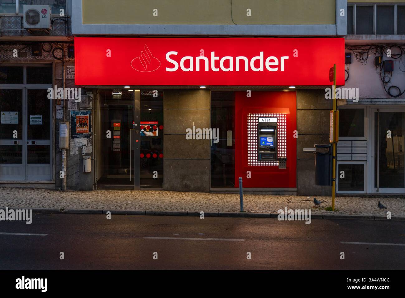 Santander Bank avec signe de logo lumineux et distributeur automatique de billets à l'extérieur la nuit Portugal. Banco Santander est une banque espagnole. Banque D'Images Santander Bank avec signe de logo lumineux et distributeur automatique de billets à l'extérieur la nuit Portugal. Banco Santander est une banque espagnole. Banque D'Images