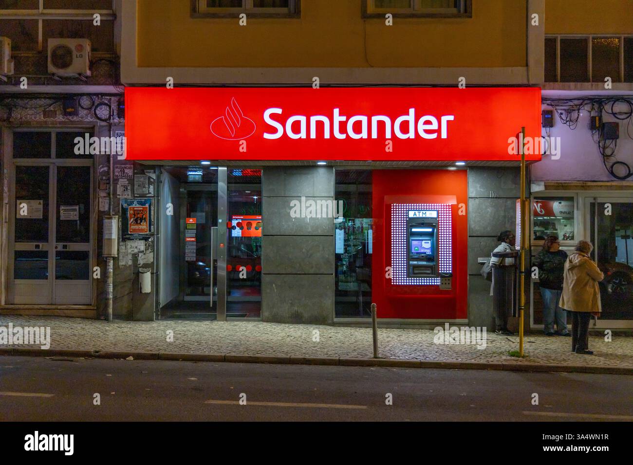 Santander Bank avec signe de logo lumineux et distributeur automatique de billets à l'extérieur la nuit Portugal. Banco Santander est une banque espagnole. Banque D'Images Santander Bank avec signe de logo lumineux et distributeur automatique de billets à l'extérieur la nuit Portugal. Banco Santander est une banque espagnole. Banque D'Images