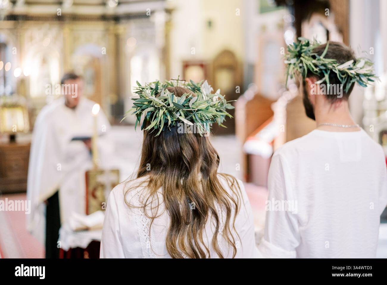Monténégro, Kotor - 07 juillet 2024 : mariés et mariés dans des couronnes se tiennent dans l'église devant le prêtre menant la cérémonie de mariage Banque D'Images