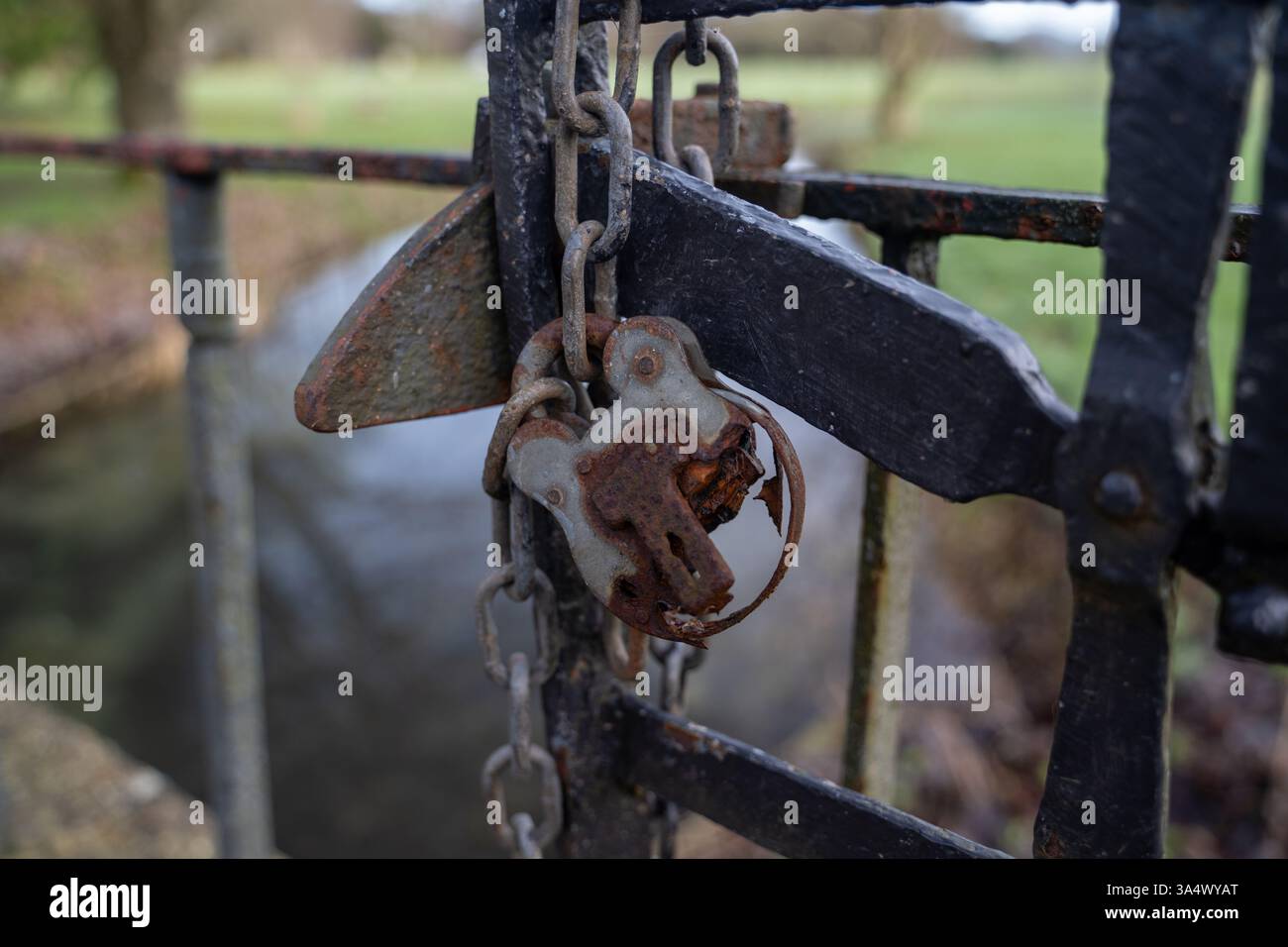 Un vieux cadenas rouillé qui a vu des jours meilleurs accroché à une chaîne sur certaines portes dans le parc de West Dean Gardens Banque D'Images