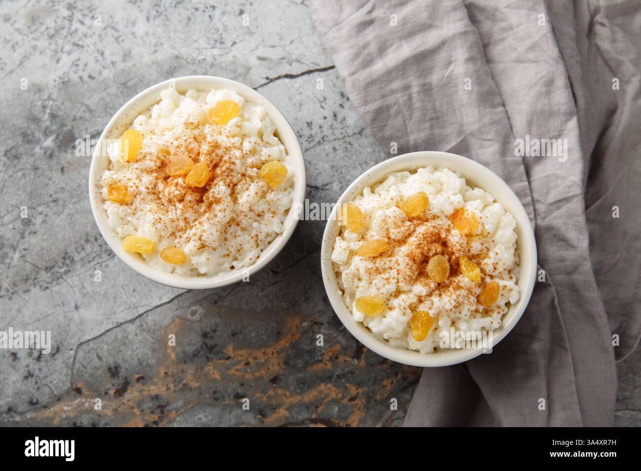 Bol de délicieux pudding de riz avec cannelle, vanille et raisins secs en gros plan sur la table. Vue horizontale de dessus Banque D'Images