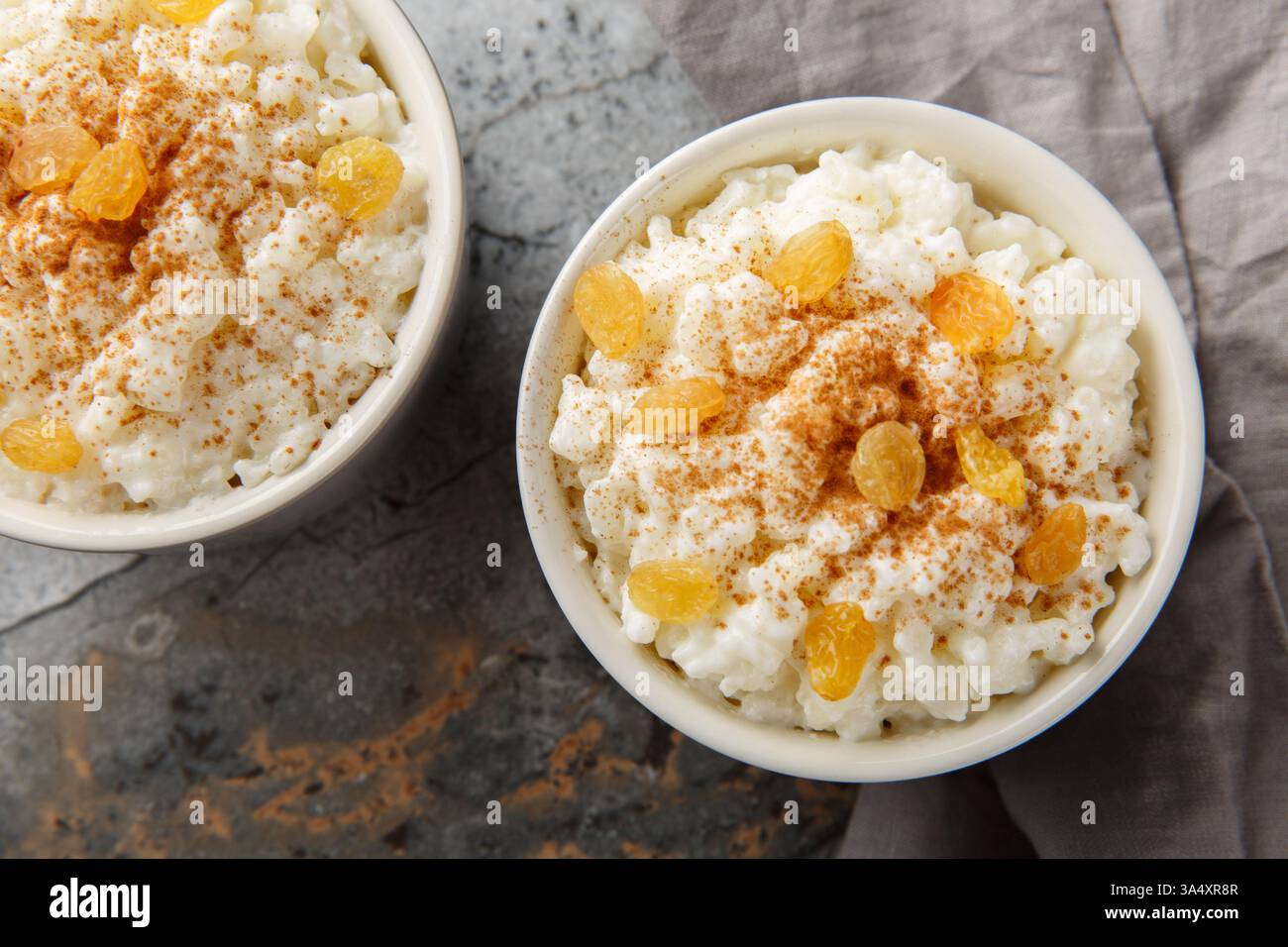 Pudding de riz sucré avec cannelle et raisins secs sur le dessus gros plan dans un ramequin sur la table. Vue horizontale de dessus Banque D'Images
