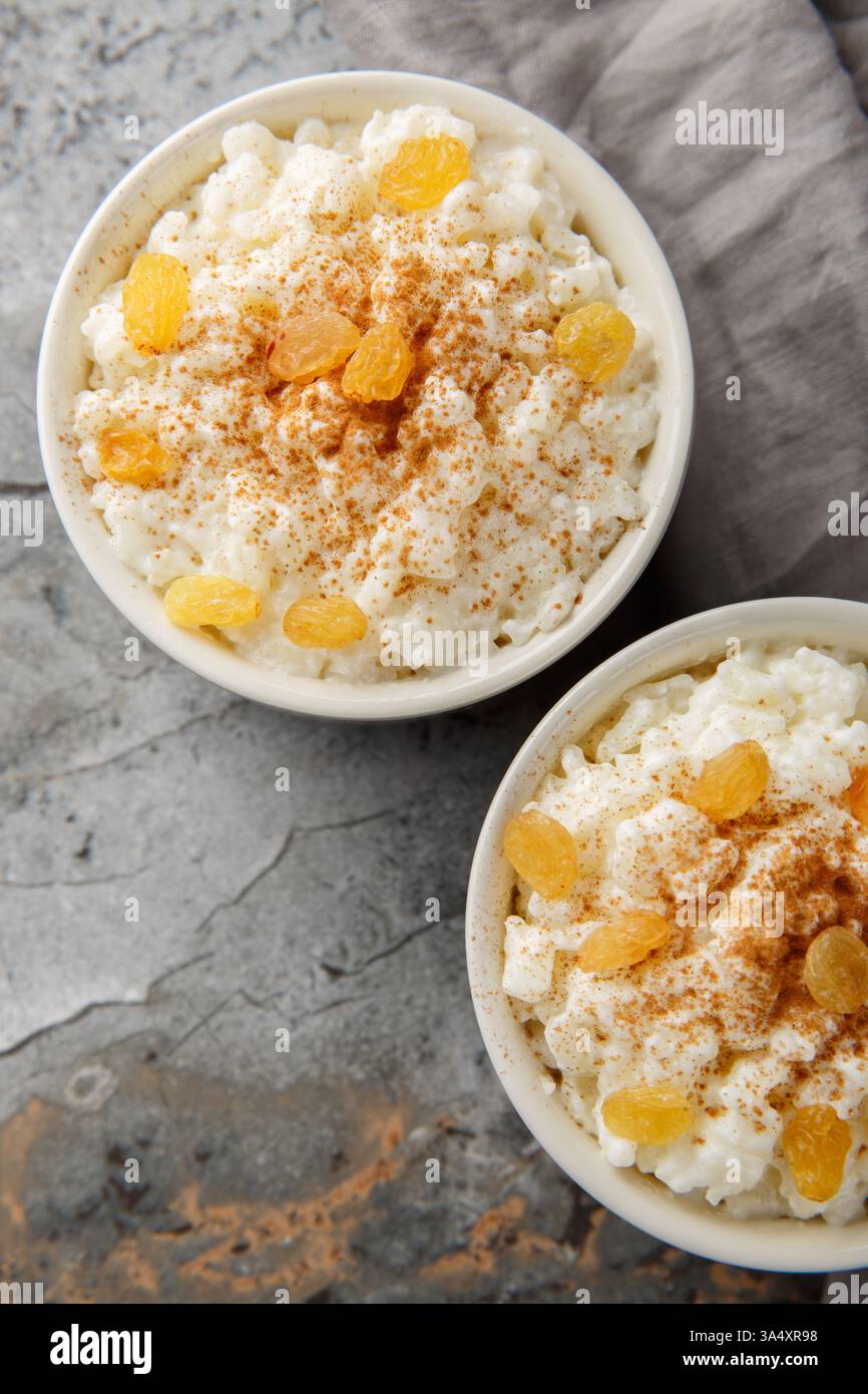 Purée de riz crémeuse avec du lait et du sucre, puis terminez avec de la cannelle, de la vanille et des raisins secs en gros plan sur le bol sur la table. Vue de dessus verticale Banque D'Images