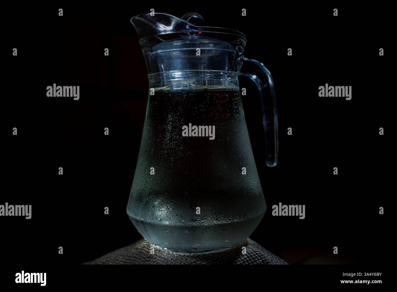 Pichet en verre d'eau sur la table. Place pour le texte, pour la publicité, les menus et les documents imprimés. Fond sombre. Banque D'Images