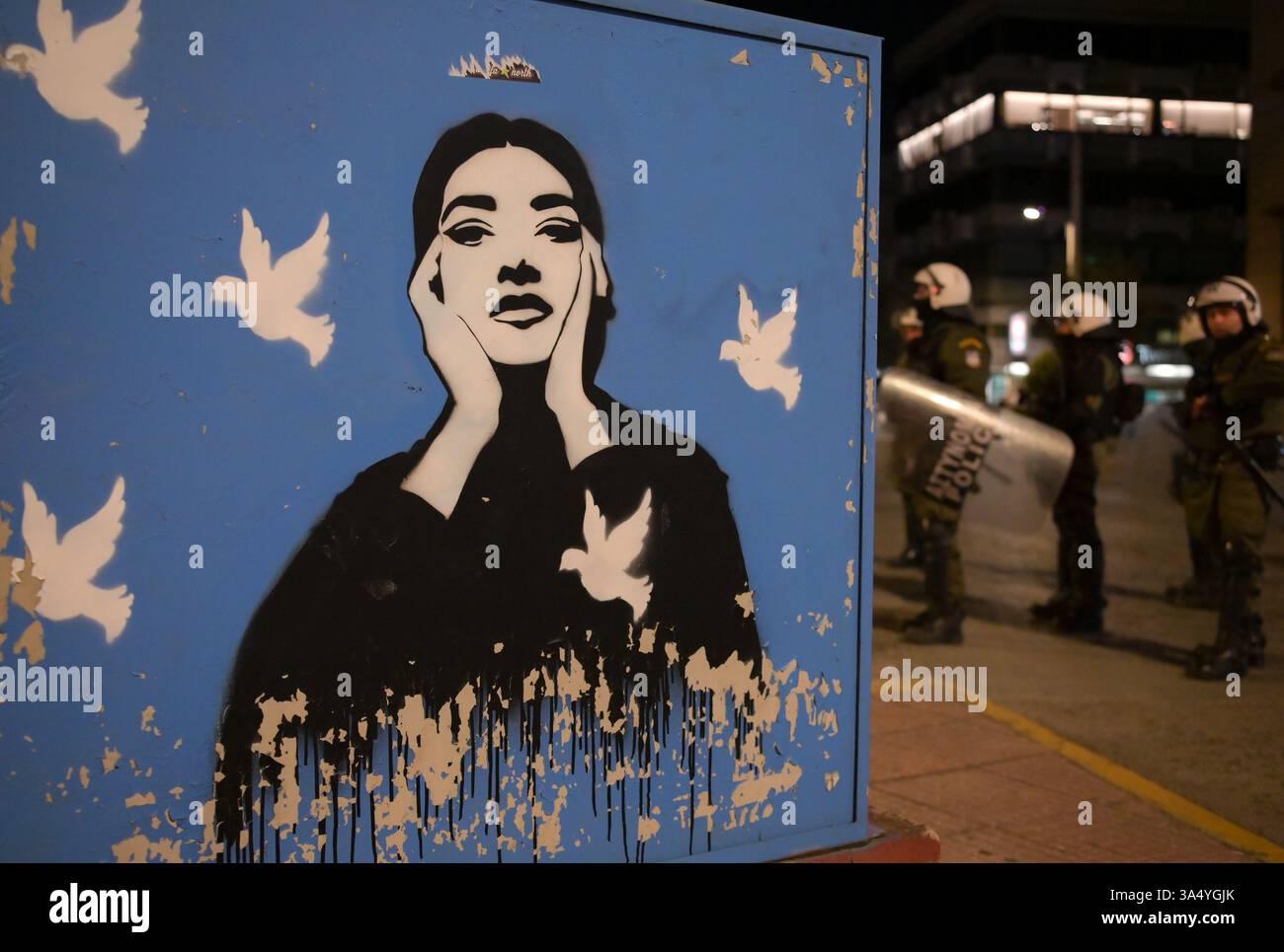 Athènes, Grèce, 19 mars 2025. Une boîte électrique est recouverte d’un graffiti de Maria Callas avec des pigeons de paix devant l’ambassade israélienne tandis que la police anti-émeute contrôle la zone lors d’un rassemblement contre les frappes aériennes de Gaza. Crédit : Dimitris Aspiotis/Alamy Live News Banque D'Images