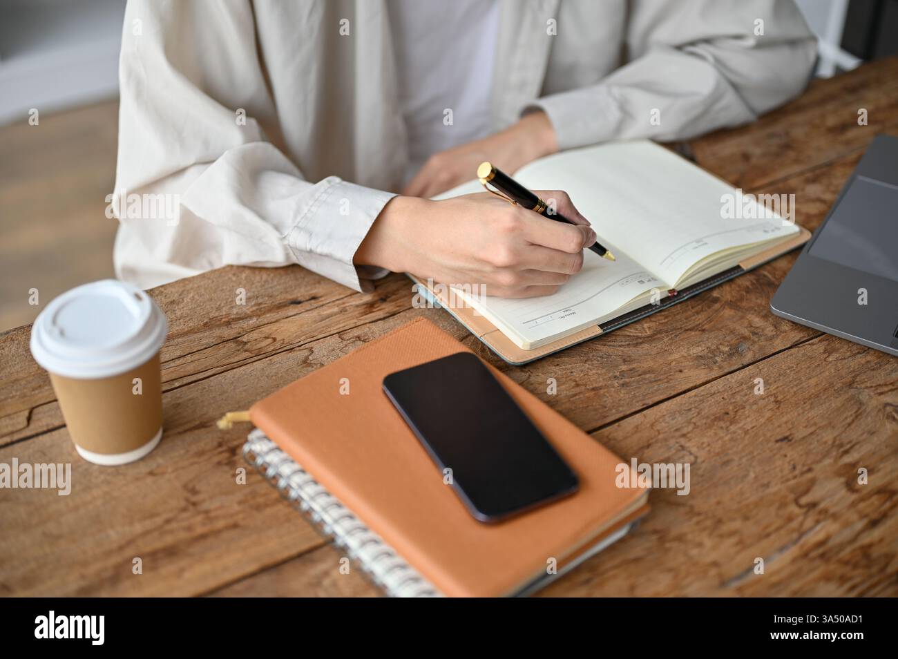 Gros plan d'un étudiant asiatique prenant des notes et lisant un manuel dans une salle d'étude. Concentrez-vous sur l'apprentissage, les habitudes d'étude et la vie universitaire. Convient pour l'enseignement, la formation et l'utilisation en classe. Banque D'Images
