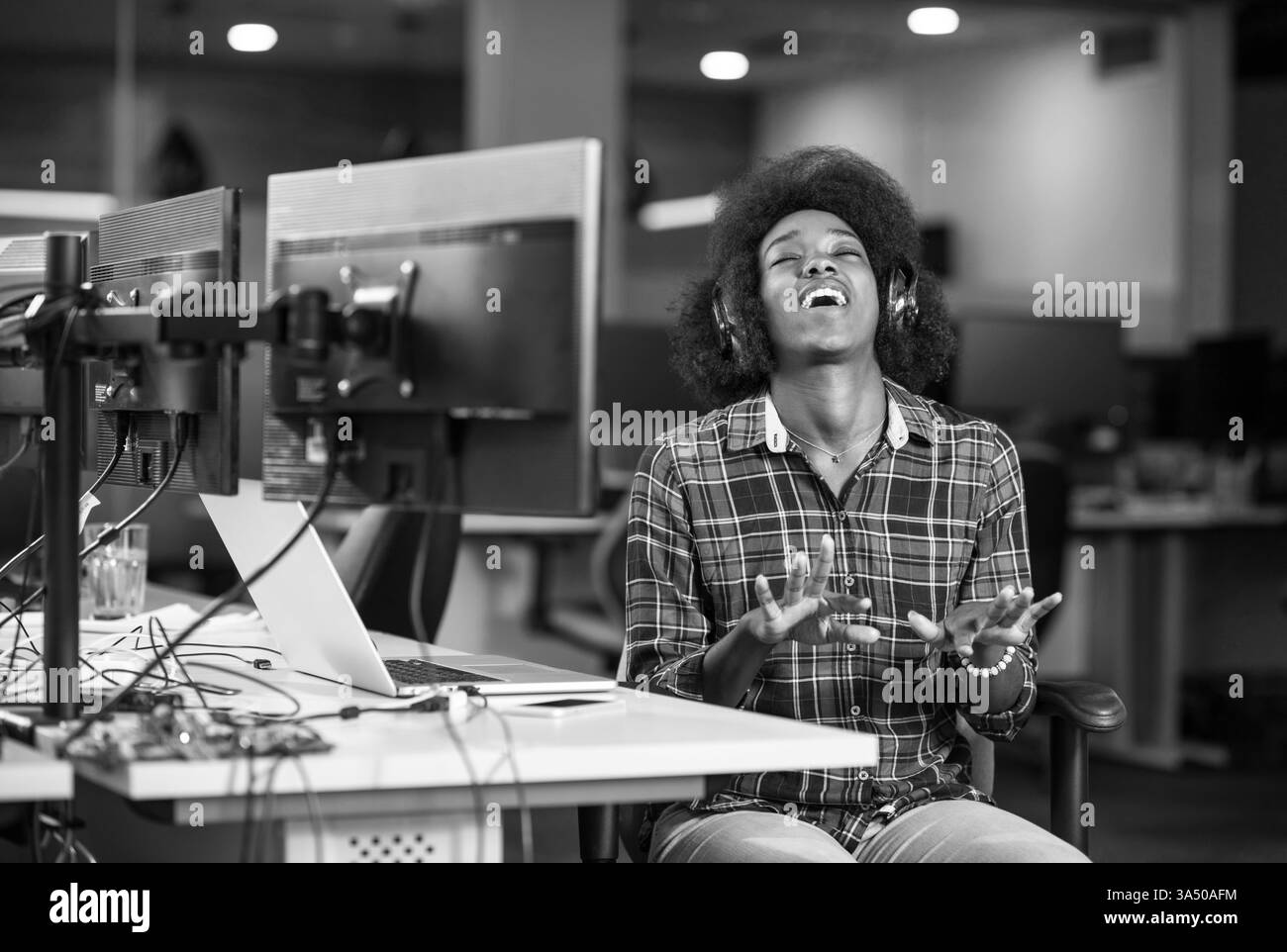 Portrait d'une jeune femme noire prospère qui aime passer un temps de qualité et joyeux tout en travaillant dans un grand bureau moderne Banque D'Images