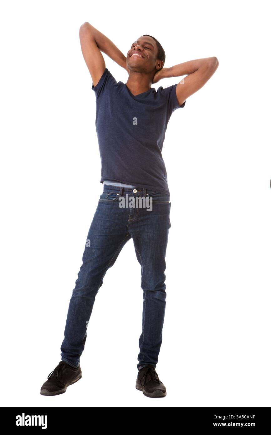 Portrait complet du corps d'un homme afro-américain heureux debout avec les mains derrière la tête sur un fond blanc. La pose détendue et confiante rend cette image adaptée aux campagnes de bien-être, de style de vie et d'énergie positive. Idéal pour les stocks d'entreprise avec une ambiance décontractée. Banque D'Images