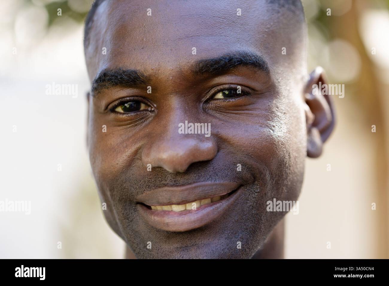 Homme souriant profitant de vacances en plein air, se sentant détendu et heureux dans la lumière du soleil Banque D'Images