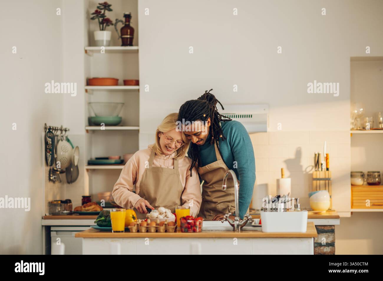 Couple interracial romantique cuisinant un repas bio dans la cuisine. Une scène domestique chaleureuse axée sur la nourriture saine et faite maison. Convient pour le style de vie, la cuisine et les fonctionnalités de la vie à la maison. Banque D'Images