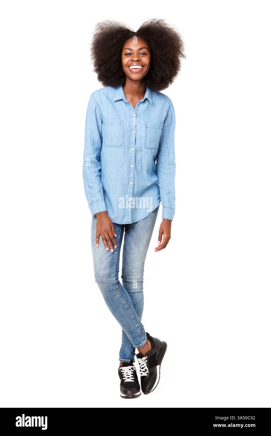 Femme noire aux cheveux afro debout avec les pieds croisés contre un fond de studio blanc. Un portrait polyvalent adapté au style de vie, à la mode et aux thèmes de style personnel. Banque D'Images