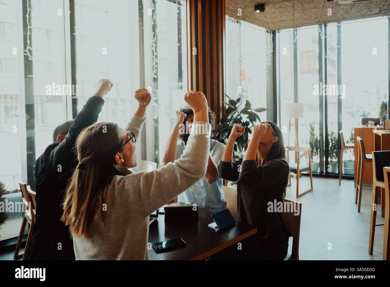 Groupe de professionnels divers levant leurs mains dans la célébration. Une image d'équipe d'entreprise moderne qui véhicule le travail d'équipe, la réussite et une culture positive en milieu de travail. Idéal pour la réussite commerciale, la collaboration et les récits de croissance de l'entreprise. Banque D'Images
