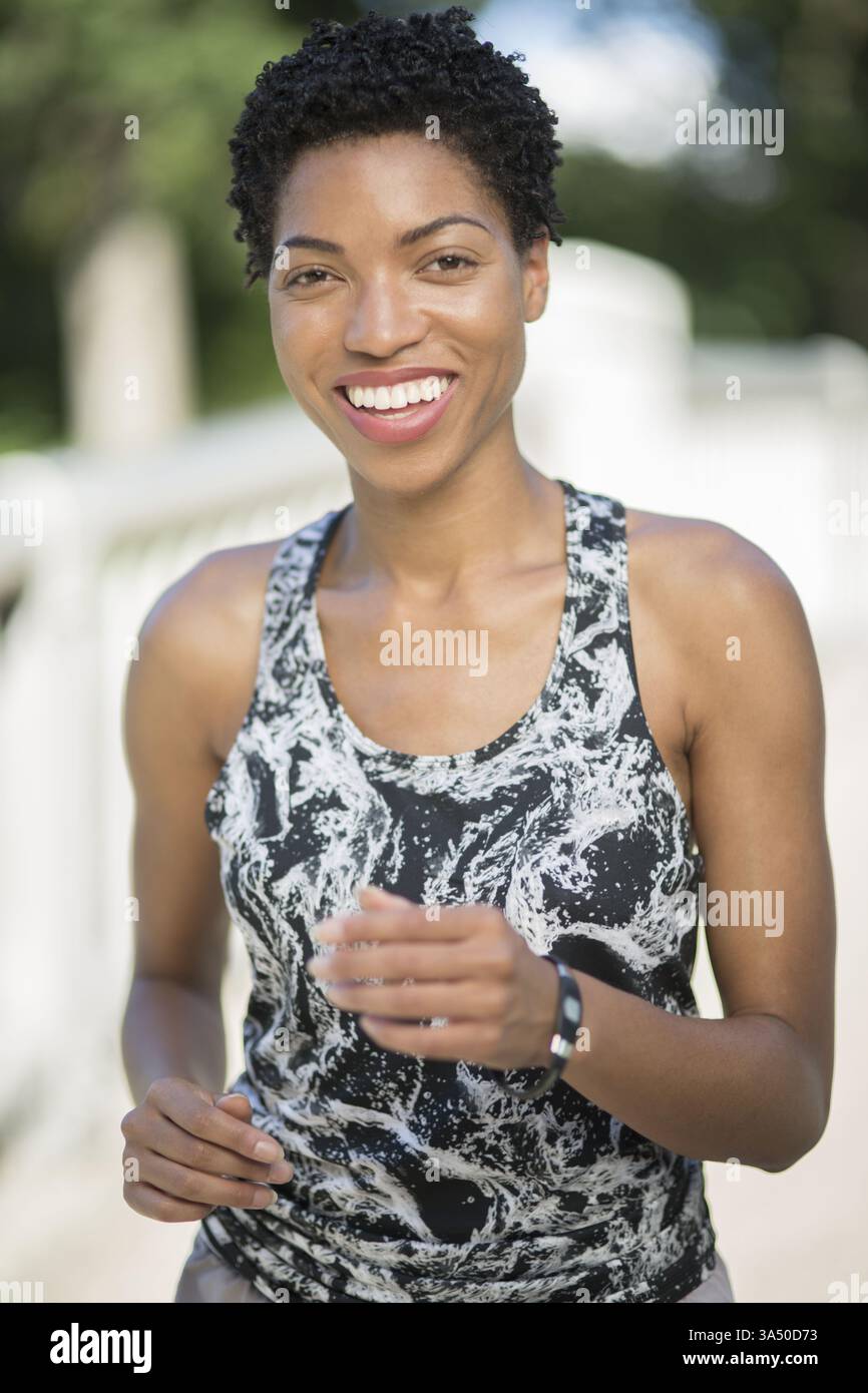 Femme noire souriante en vêtements sportifs, mettant en valeur un mode de vie sain et actif. Un portrait naturel en plein air qui véhicule confiance et vitalité. Convient aux campagnes de fitness, de bien-être et d'autonomisation des femmes. Banque D'Images
