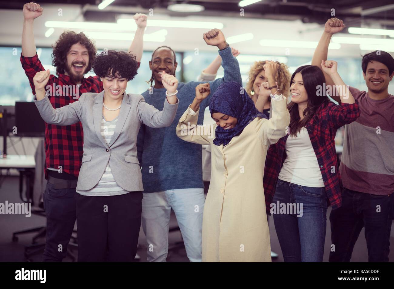 Portrait d'une équipe diversifiée de développeurs de logiciels célébrant le succès dans une startup moderne. Le groupe se tient ensemble, souriant à la caméra, transmettant le travail d'équipe et les réalisations. Parfait pour les thèmes de la technologie, des affaires et de l'entrepreneuriat dans un bureau contemporain. Banque D'Images