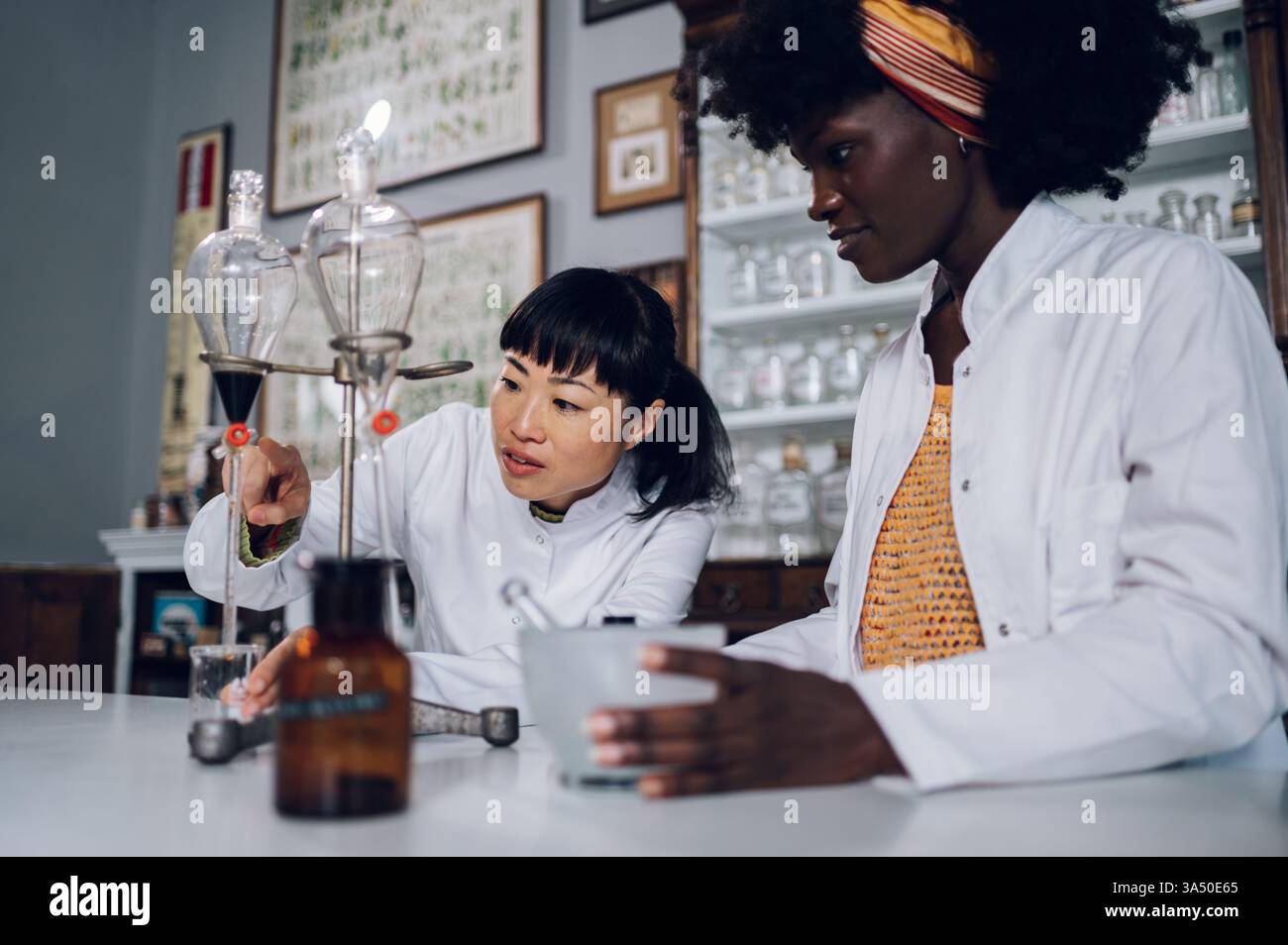Pharmaciens interraciaux debout dans une pharmacie vintage, menant une expérience et préparant des médicaments. Idéal pour les applications pharmaceutiques, médicales et de laboratoire. Banque D'Images