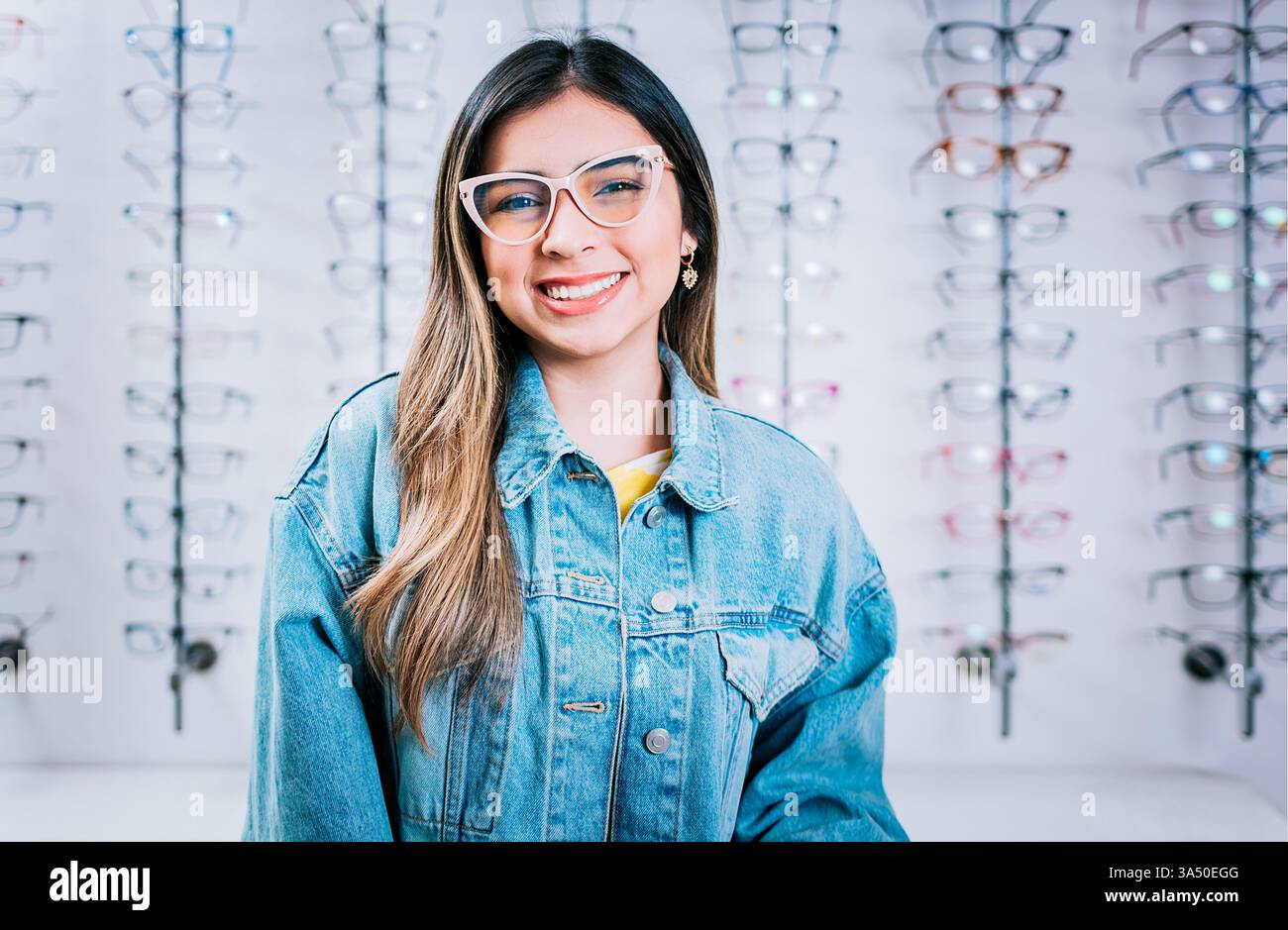 Femme souriante portant des lunettes dans un magasin de lunettes. Le portrait met en valeur les lunettes, les soins oculaires et le choix confiant du consommateur. Banque D'Images