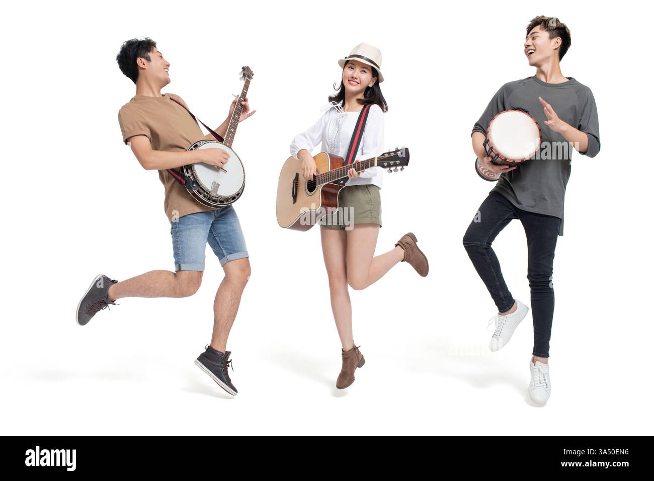 Des amis chinois joyeux se tiennent ensemble dans un studio sur un fond blanc, jouant de différents instruments de musique. Cette image de style de vie dynamique convient à la musique, à la culture des jeunes et aux thèmes de collaboration. Un portrait de groupe dynamique avec une énergie positive. Banque D'Images
