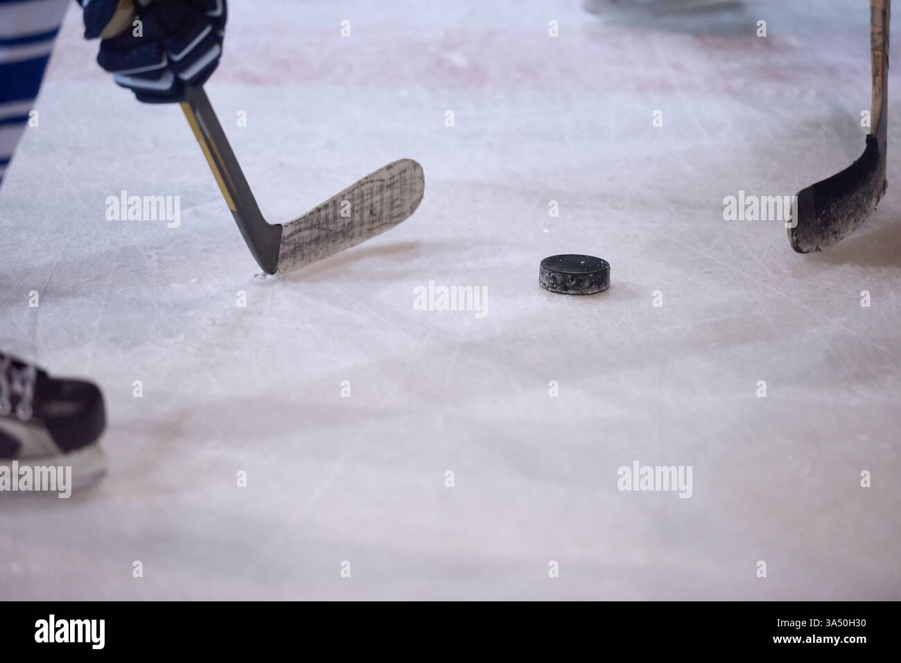 Joueur frappant la rondelle de hockey sur glace en utilisant un bâton dans le stade Banque D'Images