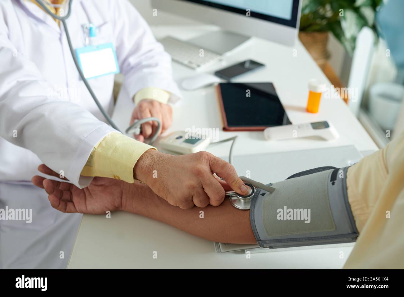 Médecin mesurant la pression artérielle d'un patient avec un tonomètre lors d'un bilan annuel. Milieu de santé adapté aux communications médicales, cliniques ou hospitalières et aux campagnes de bien-être. Banque D'Images