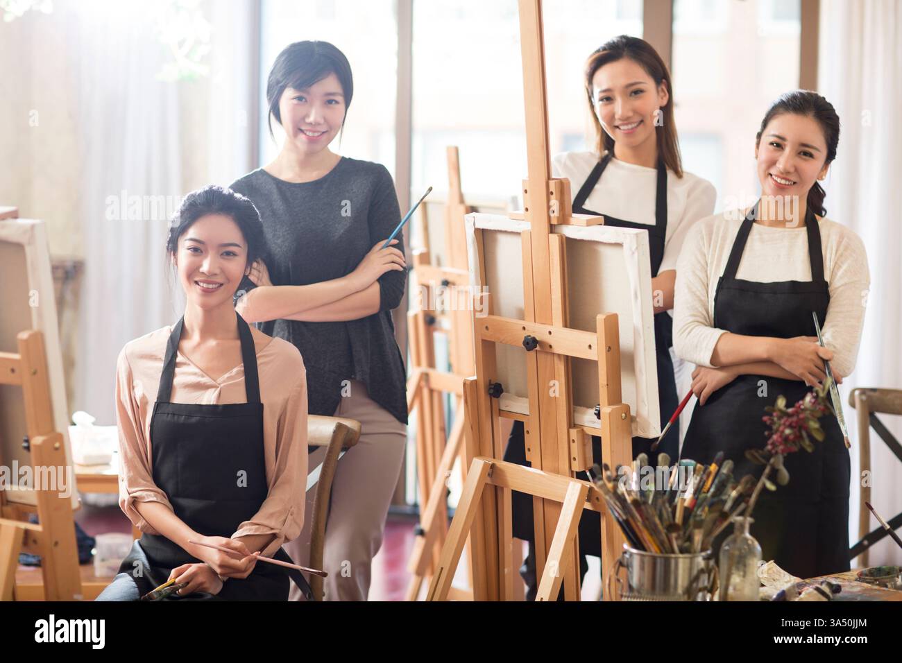 Femmes chinoises avec une enseignante dans une école d'art. La scène montre une classe d'art dans un studio avec chevalet et activité de peinture. Idéal pour l'éducation, les cours d'art, l'apprentissage en studio et les campagnes créatives. Banque D'Images