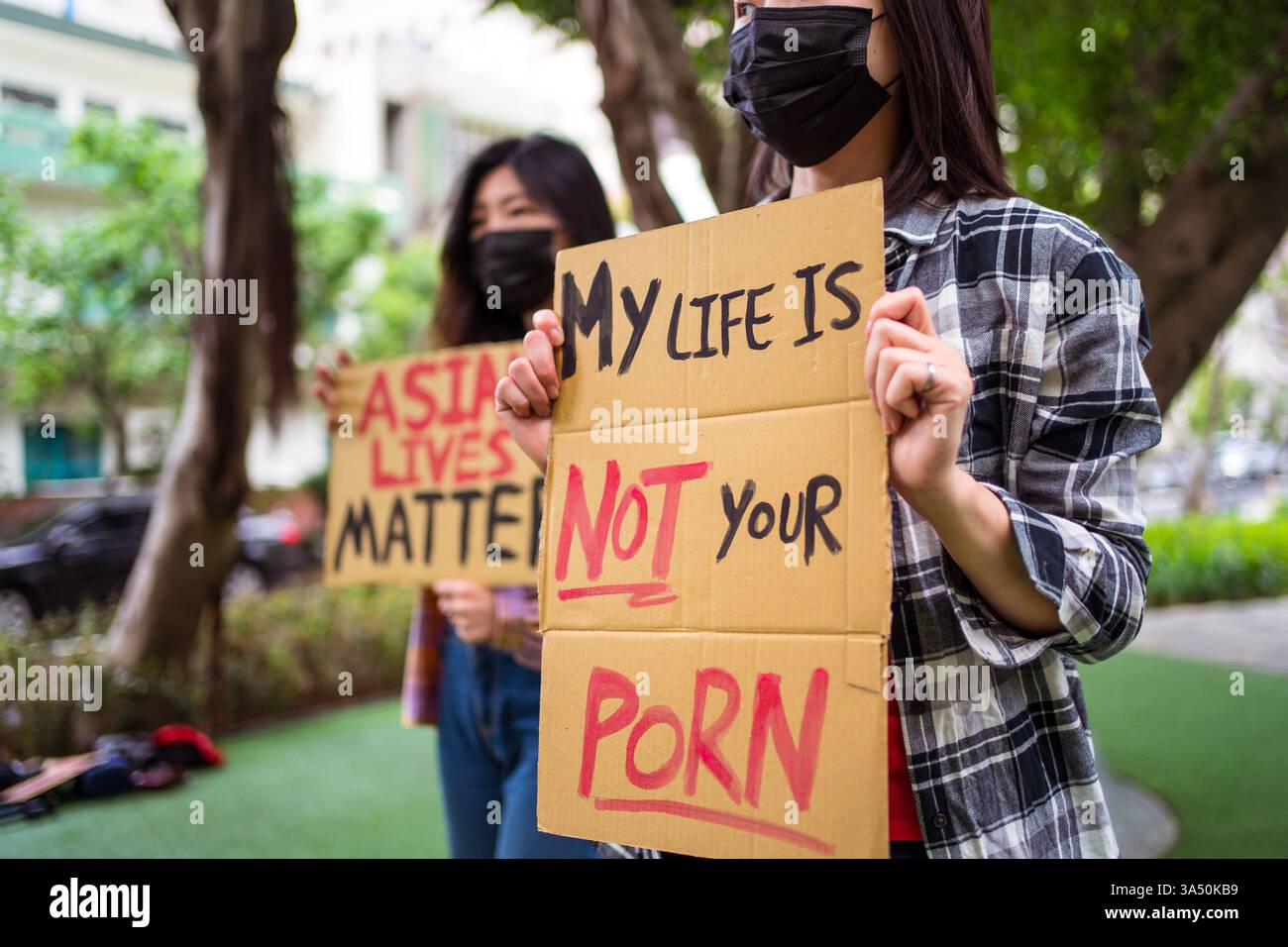 Des femmes asiatiques tiennent des pancartes lors d'un rassemblement de protestation contre la haine Stop Asian en ville. La scène communique la solidarité et la participation civique avec des banderoles et des panneaux. Parfait pour la justice sociale, la lutte contre le racisme et les campagnes communautaires. Banque D'Images