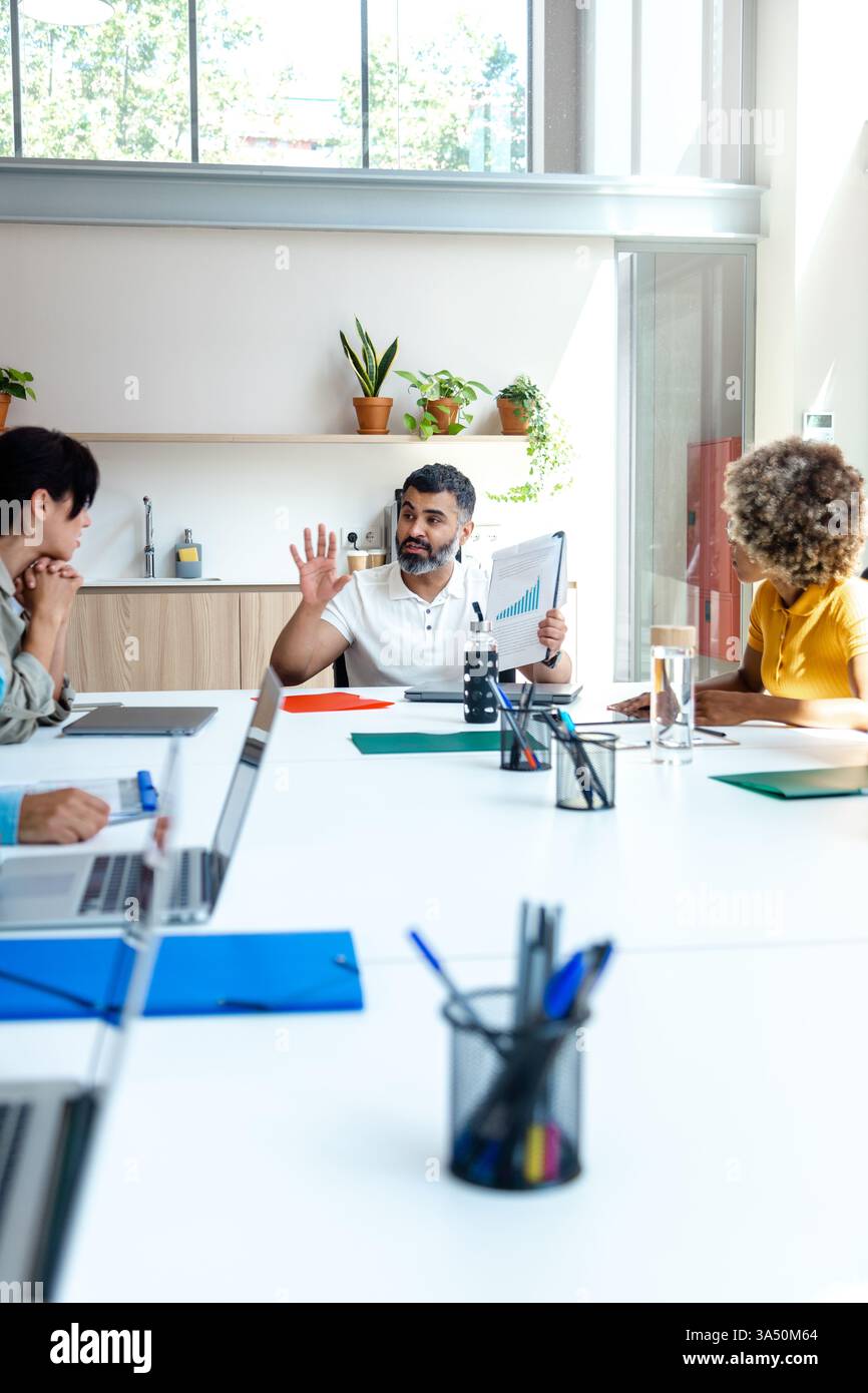 Homme indien discutant du travail avec des collègues dans une salle de conférence. Idéal pour les réunions d'affaires, le travail d'équipe et les visuels de communication d'entreprise. Banque D'Images