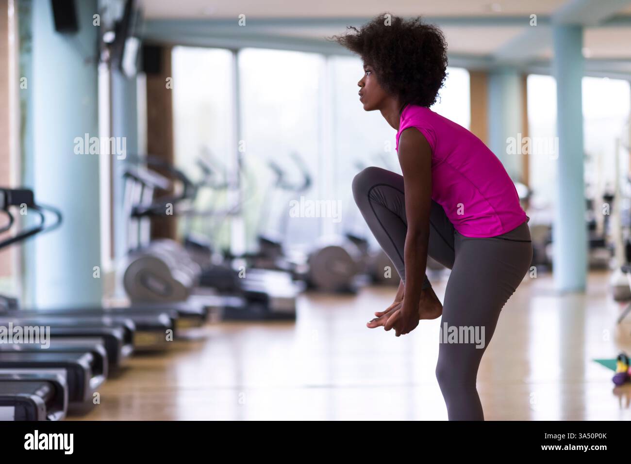 Belle jeune femme afro-américaine pratiquant le yoga dans un gymnase. Ce portrait de bien-être met en valeur la forme physique et une vie saine avec une pose calme et ciblée. Idéal pour les campagnes autour du yoga, de la pleine conscience et de la santé des femmes. Banque D'Images