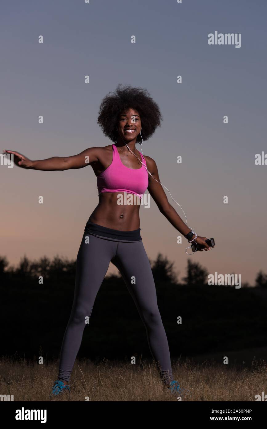 Scène active d'une jeune femme noire faisant un exercice d'étirement dans la nature lors d'une belle soirée d'été. Parfait pour les campagnes de fitness, de bien-être et de style de vie en plein air. Banque D'Images