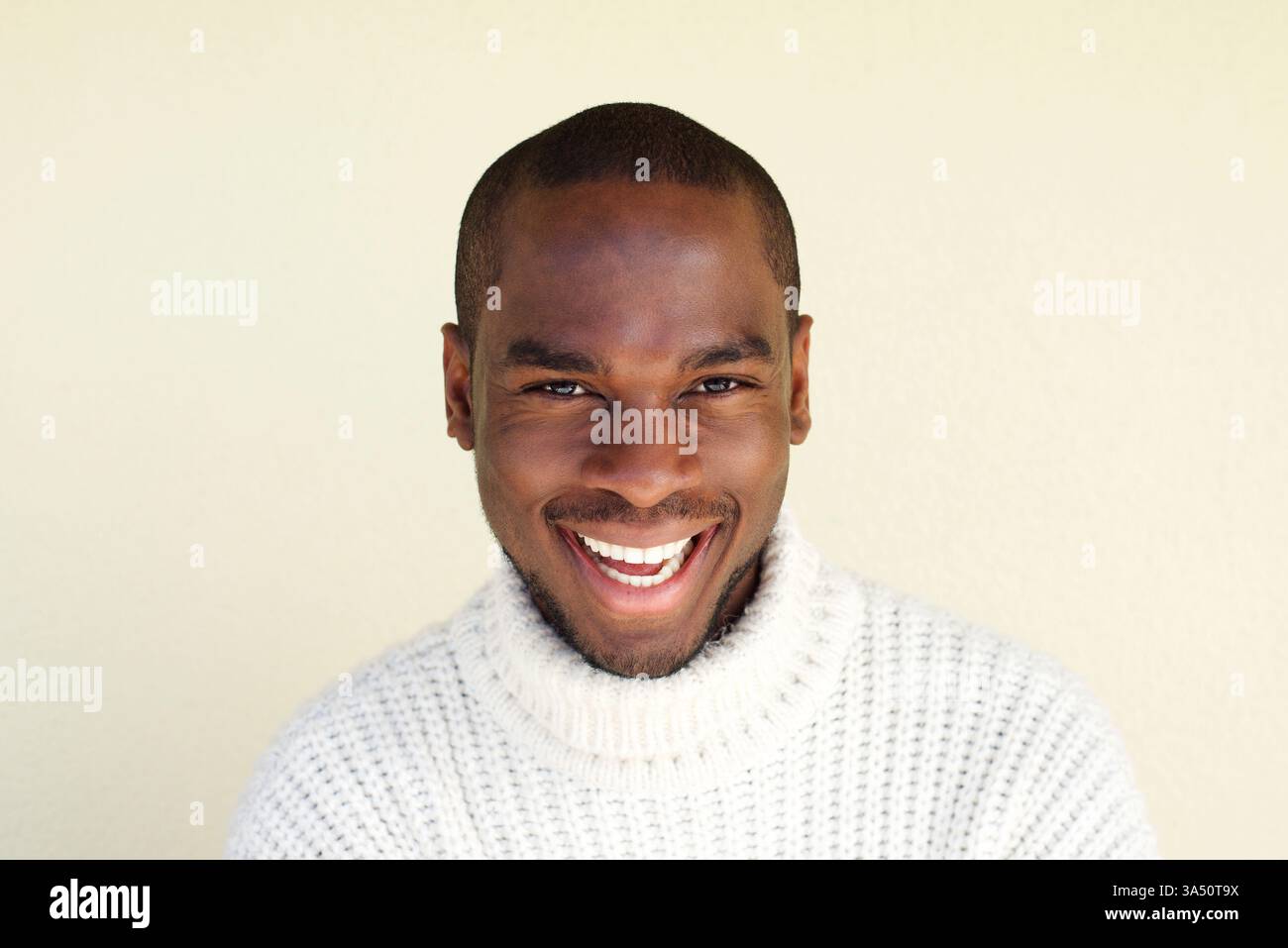 Portrait en gros plan d'un homme noir joyeux contre un mur neutre, exsudant confiance et chaleur. Cette capture d'écran conviviale est parfaite pour les images de style de vie, de marque personnelle et de marketing avec un espace libre pour la copie. Banque D'Images
