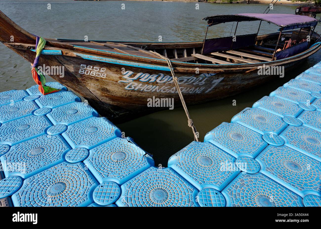 Bateau à longue queue amarré à la jetée flottante d'East Railay, avec sa coque en bois montrant des signes d'âge Banque D'Images