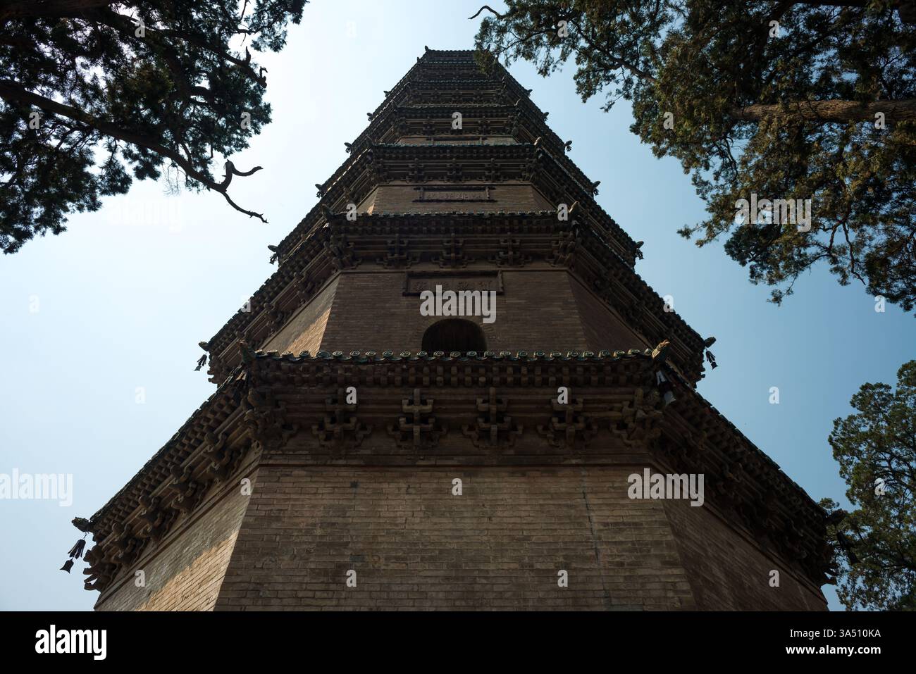 Vue en bas angle d'une pagode traditionnelle aux murs ornés contre un ciel bleu dans le Shanxi, en Chine. La scène historique du temple capture l'architecture bouddhiste et le patrimoine culturel. Parfait pour les photos de voyage, les caractéristiques de destination et la photographie architecturale. Banque D'Images