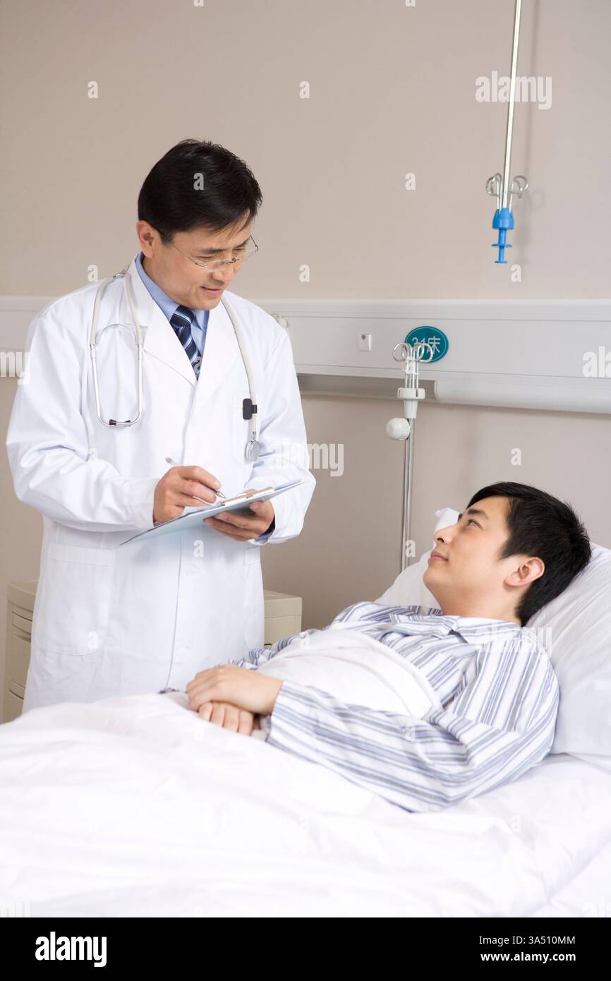 Médecin chinois examinant un patient en milieu hospitalier. Cette scène transmet les soins, la confiance et le bien-être, adapté aux services de santé et aux communications médicales. Banque D'Images