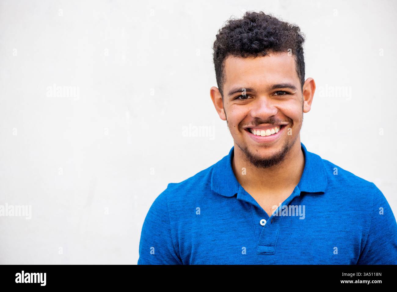 Gros plan portrait d'un homme de race mixte souriant avec une barbe sur un fond blanc. Un headshot épuré et moderne adapté aux modes de vie, à la mode et aux communications professionnelles. Idéal pour le branding personnel et les images accessibles. Banque D'Images