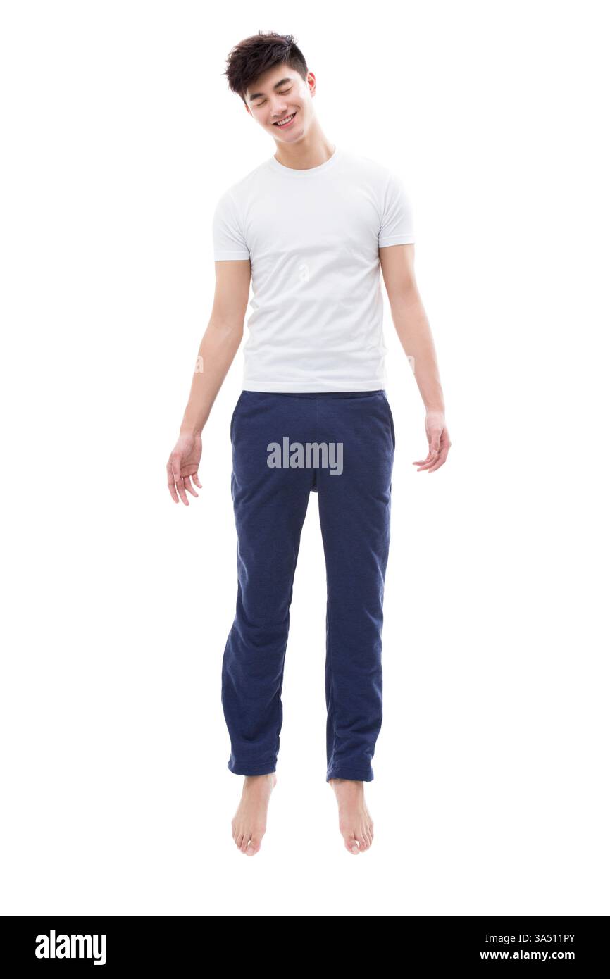 Le jeune homme chinois semble dormir dans les airs, créant un moment surréaliste et fantaisiste. Le cliché franc évoque l'imagination et la lévitation. Banque D'Images