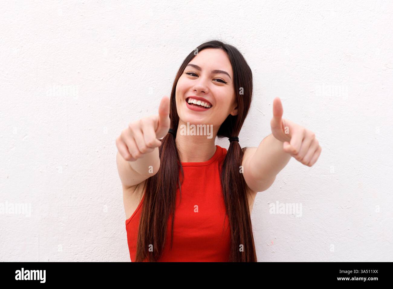 Gros plan portrait d'une jeune femme multiraciale positive donnant un pouce vers le haut. Elle sourit chaleureusement, véhiculant confiance et motivation. Idéal pour le style de vie, la réussite et les thèmes de développement personnel. Banque D'Images