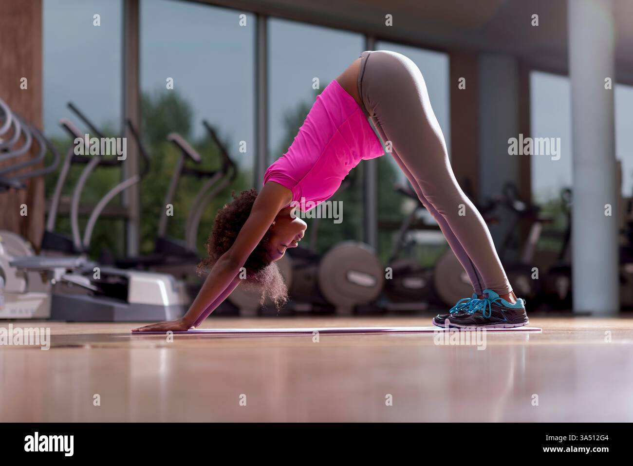 Belle jeune femme afro-américaine pratiquant le yoga dans un gymnase. Une image de bien-être calme et ciblée, adaptée aux histoires de fitness, de bien-être et de mode de vie actif. Banque D'Images