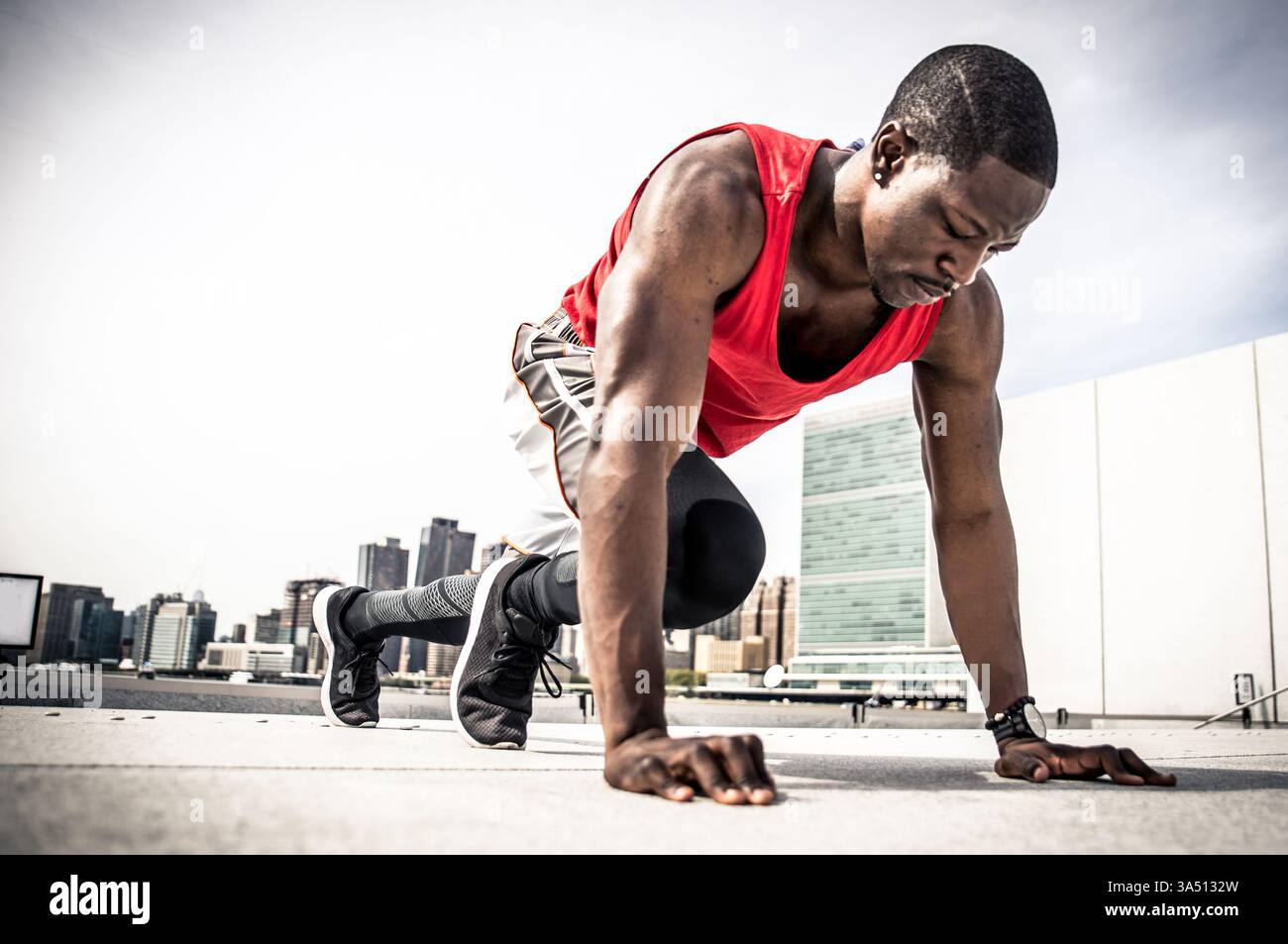Homme afro-américain concentré effectuant des exercices d'alpinisme en plein air pendant la journée. Idéal pour les campagnes de fitness et de santé qui transmettent détermination et énergie. Le cadre extérieur avec des éléments Skyline ajoute un style de vie dynamique et actif. Banque D'Images