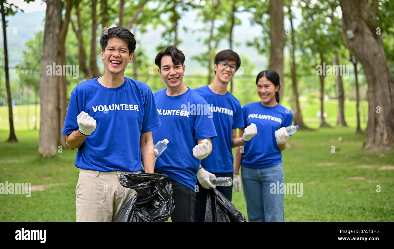 Un groupe de jeunes bénévoles asiatiques se tient ensemble dans un parc public, levant les poings pour montrer son soutien à un nettoyage communautaire. La scène met en lumière le travail d'équipe, la charité et l'action environnementale. Parfait pour les initiatives de RSE, les campagnes de bénévolat et l'engagement communautaire. Banque D'Images