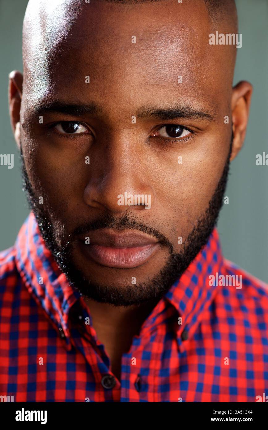 Gros plan portrait d'un bel homme noir contre un mur gris. L'expression confiante et élégante convient au style de vie moderne et à la photographie de mode, à la marque et aux campagnes de style personnel. Banque D'Images